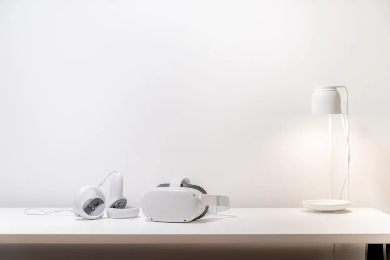 Oculus-headset ja sen kaksi ohjainta valkoisen lampun kanssa.
