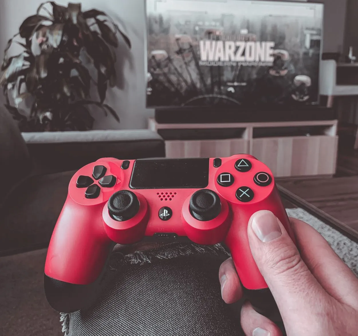 Hraní na systému PS4 s červeně zbarveným ovladačem.