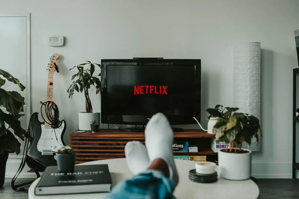 Netflix'in gösterildiği bir televizyon ve beyaz çorap giyen bir adam